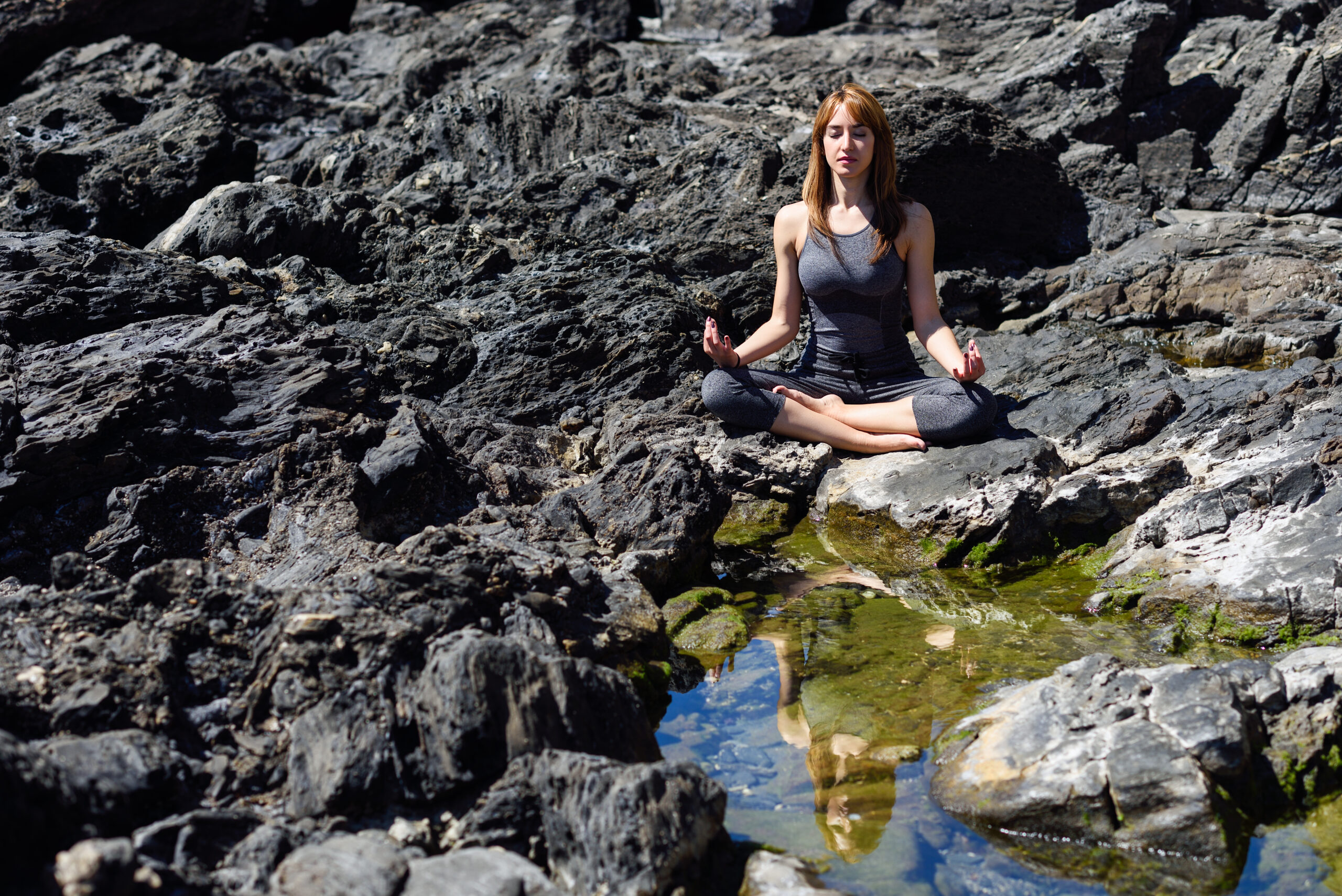 Young woman doing yoga in nature. Female wearing sport clothes in lotus figure.