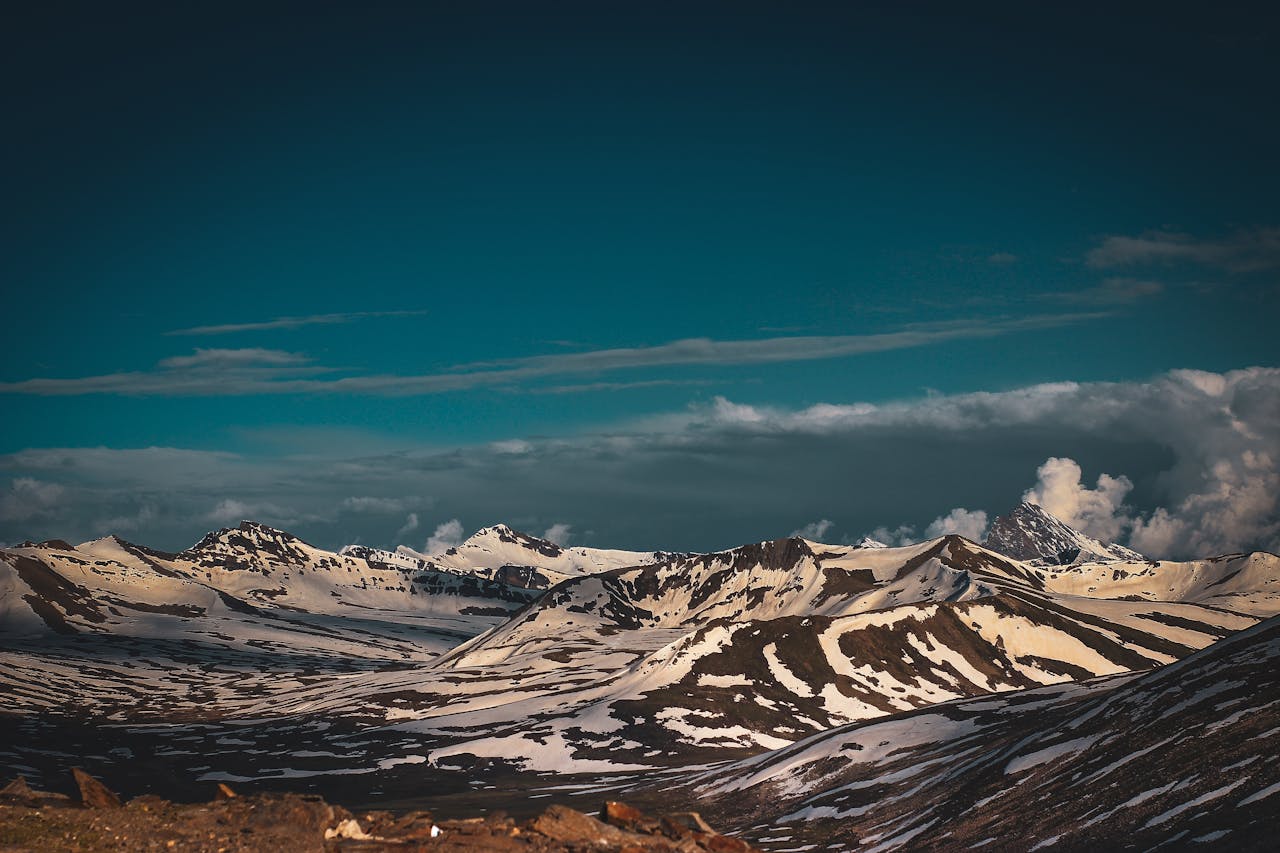 services-01 A breathtaking view of snow-capped mountains against a dramatic sky at sunset.