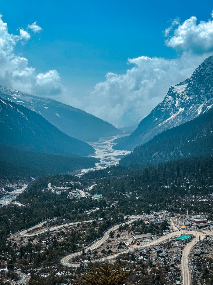 why-choose-us Breathtaking aerial view of Yumthang Valley's snow-capped mountains and serpentine roads.